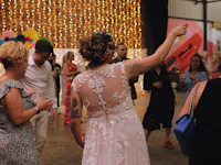 a group of people dancing at a wedding in a warehouse