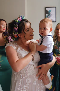 a woman in a wedding dress holding a baby