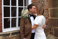 a bride and groom kissing in front of a window