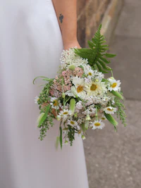 a bride holding a bouquet of flowers and ferns