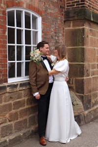 a bride and groom posing in front of a brick wall