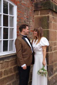 a bride and groom standing in front of a brick wall
