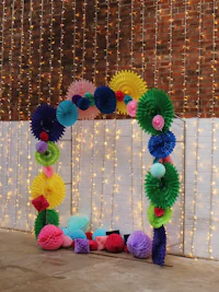 a colorful paper pom pom arch in front of a brick wall