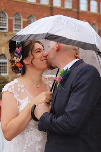 a bride and groom kiss under an umbrella