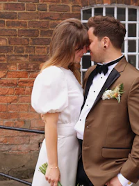 a bride and groom embracing in front of a brick building