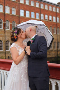 a bride and groom kissing under an umbrella