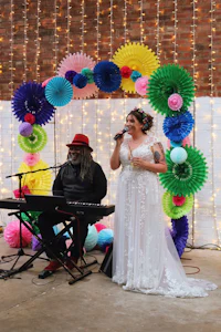 a bride and groom singing in front of colorful paper lanterns