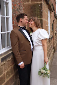 a bride and groom posing in front of a brick wall