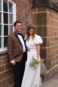 a bride and groom posing in front of a brick building