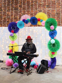 a man playing a keyboard in front of a colorful backdrop